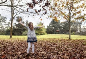 Laughing girl throwing autumn leaves in the air
