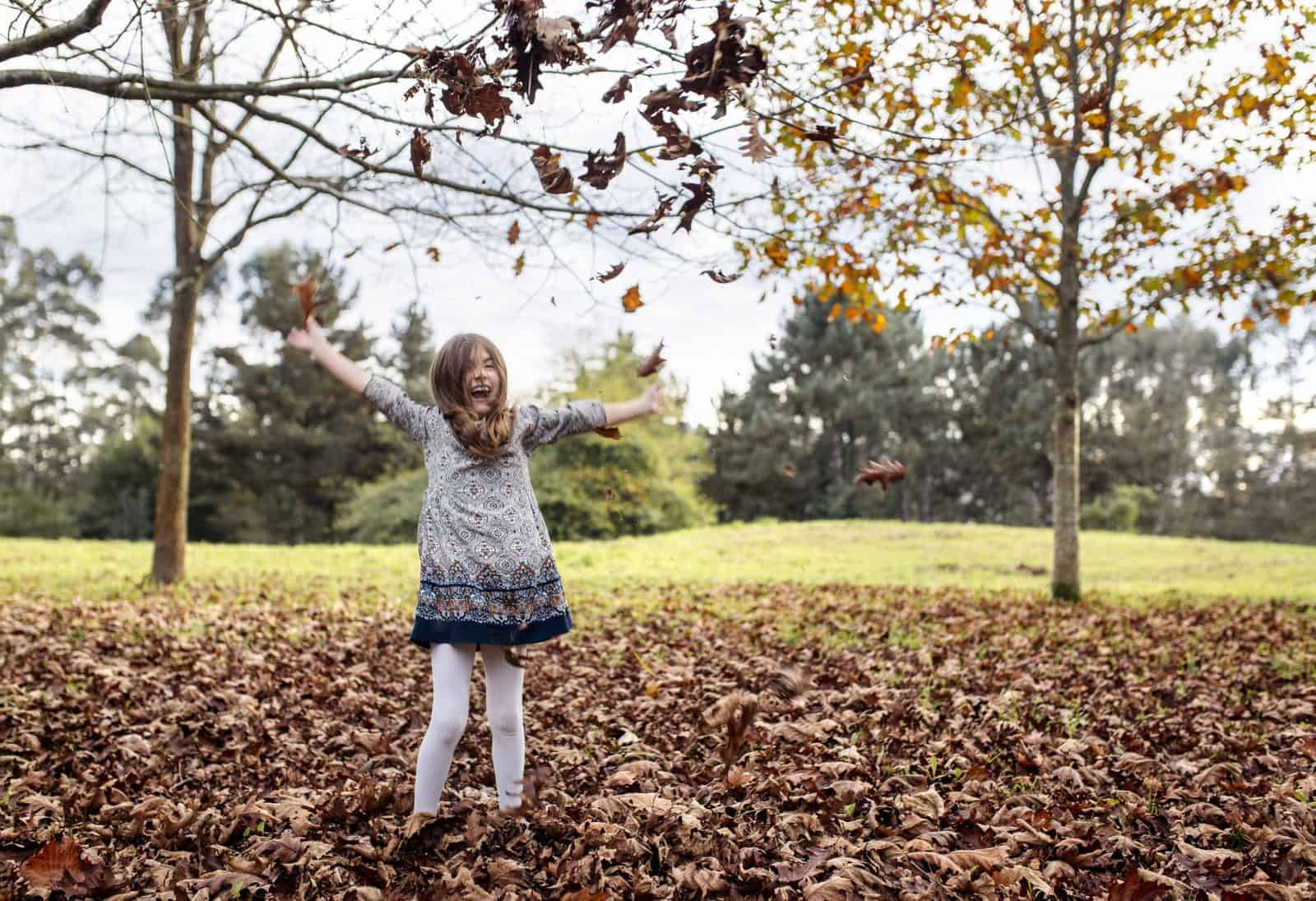 Laughing girl throwing autumn leaves in the air