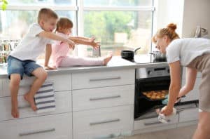 Young mother and kids tasting biscuits in kitchen