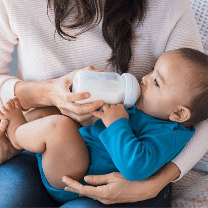 nanny feeding infant infant with bottle