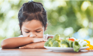 Child refusing to eat a plate of vegetables