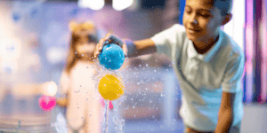 science of lay with boy balancing two balls in stream of water